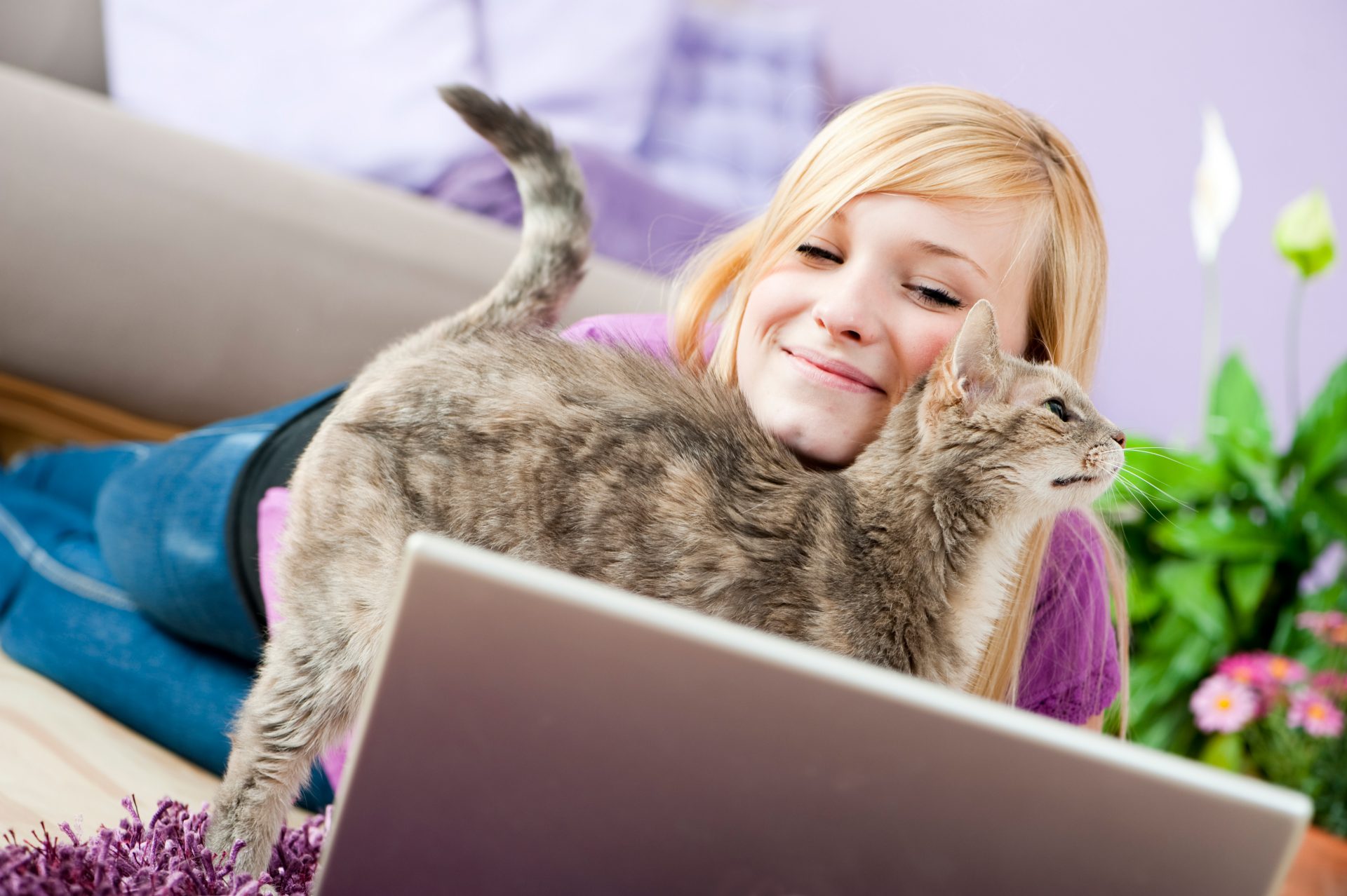 how to hire a cat sitter featured image of a girl with a cat in front of a laptop
